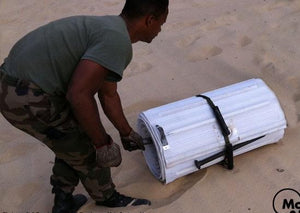 Man in military uniform with white rolled up Mobi-Tracks on sand